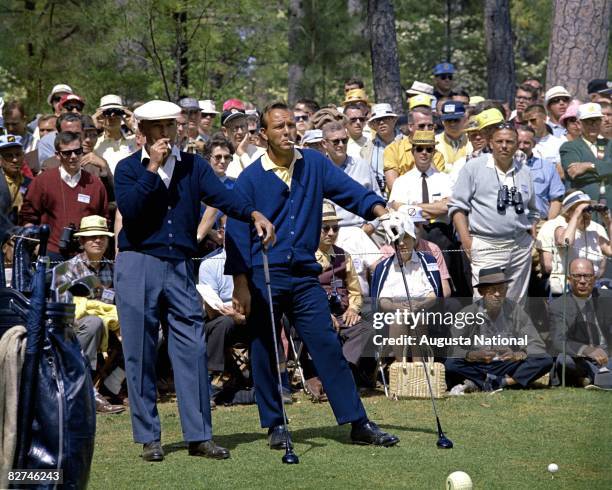 Ben Hogan and Arnold Palmer smoke as they wait in front of a gallery to play their tee shot on the second hole during the 1966 Masters Tournament at...