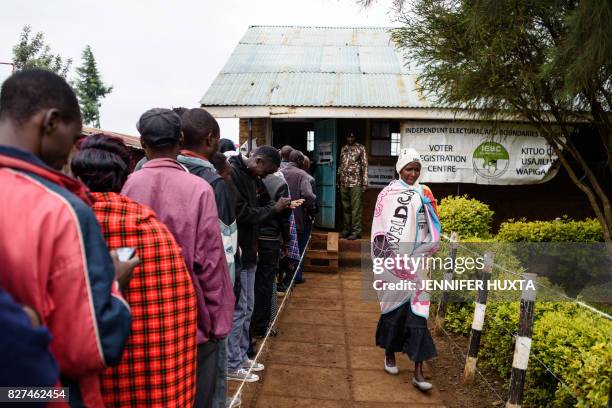 People wait in line to cast their ballot in the general elections at a polling station at Langas Primary School in the Rift Valley town of Eldoret,...