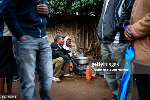 Woman prepares tea for queing voters waiting to cast their ballot in the general elections at a polling station at Langas Primary School in the Rift...