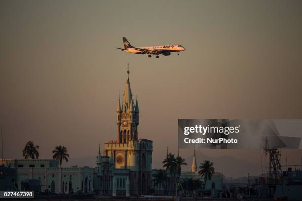 Rio de Janeiro has sunny and hot afternoon in winter. In this image, Azul's airplane overhead fleets historic building from Fiscal Island during...