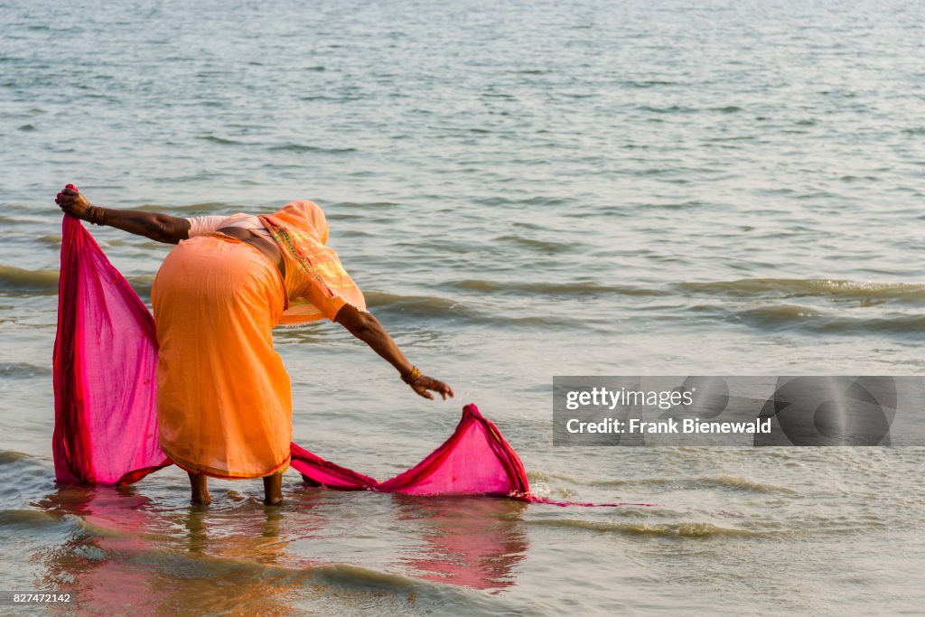 A woman is washing her sari on the beach of Ganga Sagar,...