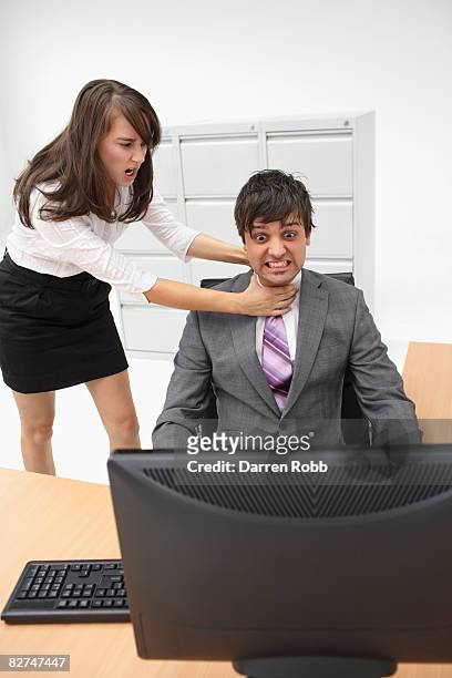 businesswoman strangling a businessman at desk - women being strangled foto e immagini stock
