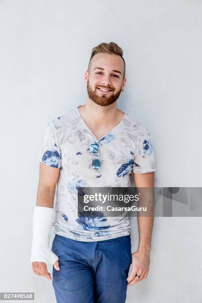 portrait of handsome young man with broken arm - broken arm stock pictures, royalty-free photos & images
