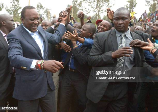 Kenya's President Uhuru Kenyatta greets supporters after voting at a polling station during the August 8, 2017 presidential election in Gatundu,...