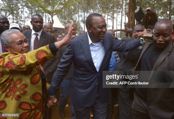 Kenya's President Uhuru Kenyatta holds the hand of First Lady Margaret Kenyatta, as they greet supporters after voting at a polling station during...