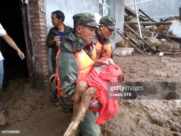 Rescuers carry a survivor at the site of a landslide in Puge in China's southwestern Sichuan province on August 8, 2017. A landslide triggered by...