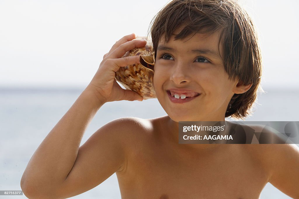 Boy And Shells Boy On The Beach Holding A Shell On The Ear High-Res Stock Photo ...