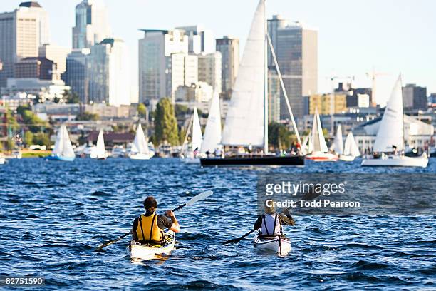 couple paddling kayaks in city lake - seattle people stock pictures, royalty-free photos & images