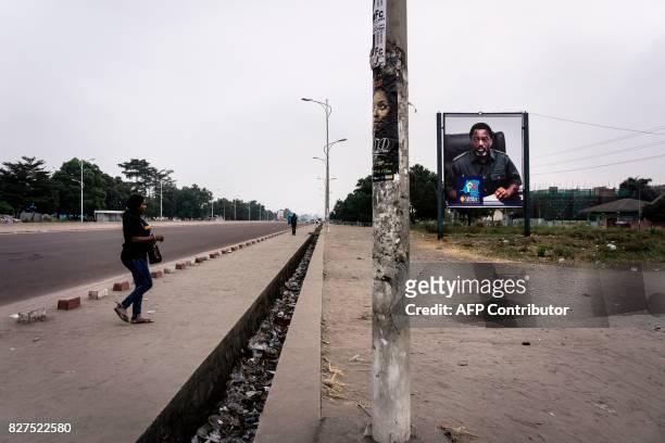Congolese women crosses an empty boulevard in Kinshasa with a placard of President of the Democratic Republic of Congo Joseph Kabila as the...