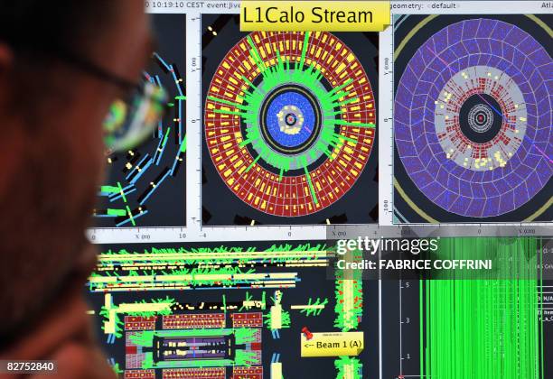 European Organization for Nuclear Research scientist looks at computer screens showing traces on the Atlas experiment of the first protons injected...