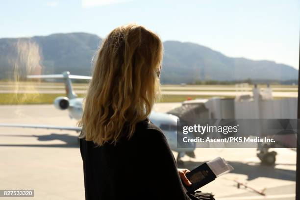 woman looks out to jet on tarmac, at airport - canadian passport stock-fotos und bilder