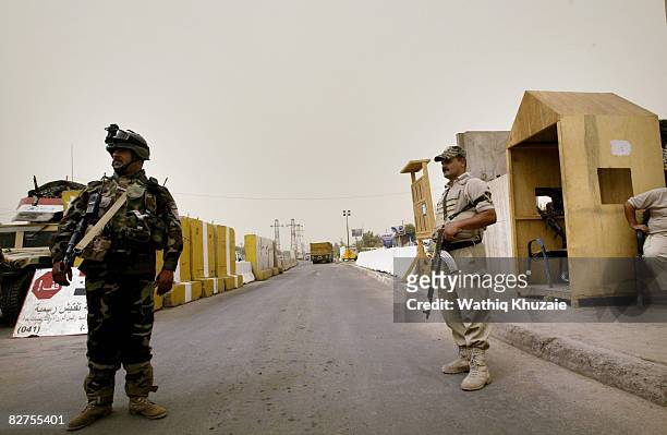 An Iraqi awakening Council member stands guard as an Iraqi army solider is seen at a checkpoint September 10, 2008 in Gazaliyah neighborhood north...