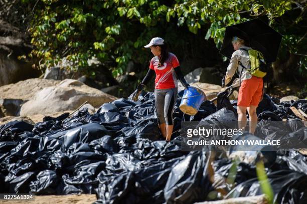 Volunteers help remove washed up palm oil from a beach as they stand amongst a pile of black bin bags on Hong Kong's outlying Lamma Island on August...