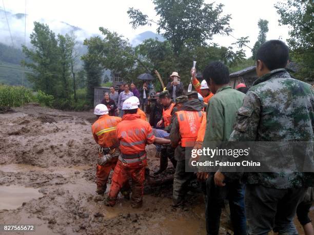 Rescuers carries out an injured man after a landslide in Gengdi village on August 08, 2017 in Puge, China. A landslide destroyed 71 rooms in the...