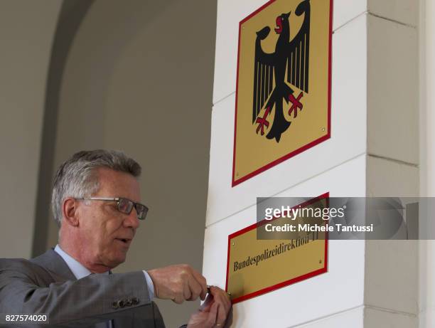 German Interior Minister Thomas de Maziere secures a door sign reading Bundespolizei or Federal Police during the opening of the new Headquarters on...