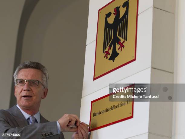 German Interior Minister Thomas de Maziere secures a door sign reading Bundespolizei or Federal Police during the opening of the new Headquarters on...