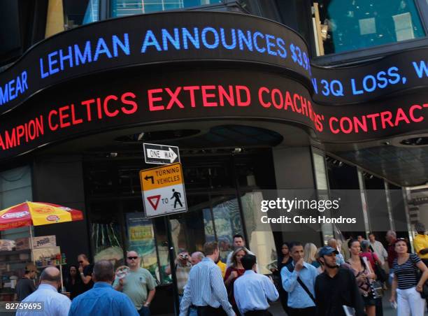 People walk under a ticker sign announcing Lehman Brothers financial losses September 10, 2008 in New York. Lehman Brothers plans to sell a majority...