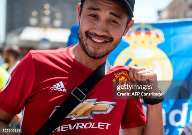 Manchester United supporter poses in the fan zone in front of a FC Real Madrid flag in Skopje on August 8 ahead of the UEFA Super Cup football match...