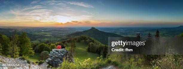 burg hohenzollern (hohenzollern castle) with an unrecognizable couple watching the sunset - panorama (baden-württemberg/ germany) - burg hohenzollern stockfoto's en -beelden