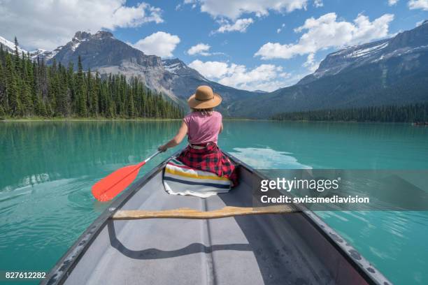 jeune femme pagayant rouge canoë sur le lac turquoise - yoho national park photos et images de collection
