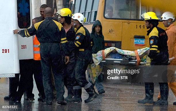 Rescuers carry on a stretcher the dead body of Pedro Pablo, killed by the collapsing of a building on September 10, 2008 at Havana's Malecon, caused...