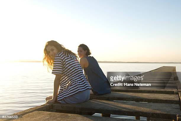 two young woman on the edge of a dock - montevideo stock pictures, royalty-free photos & images