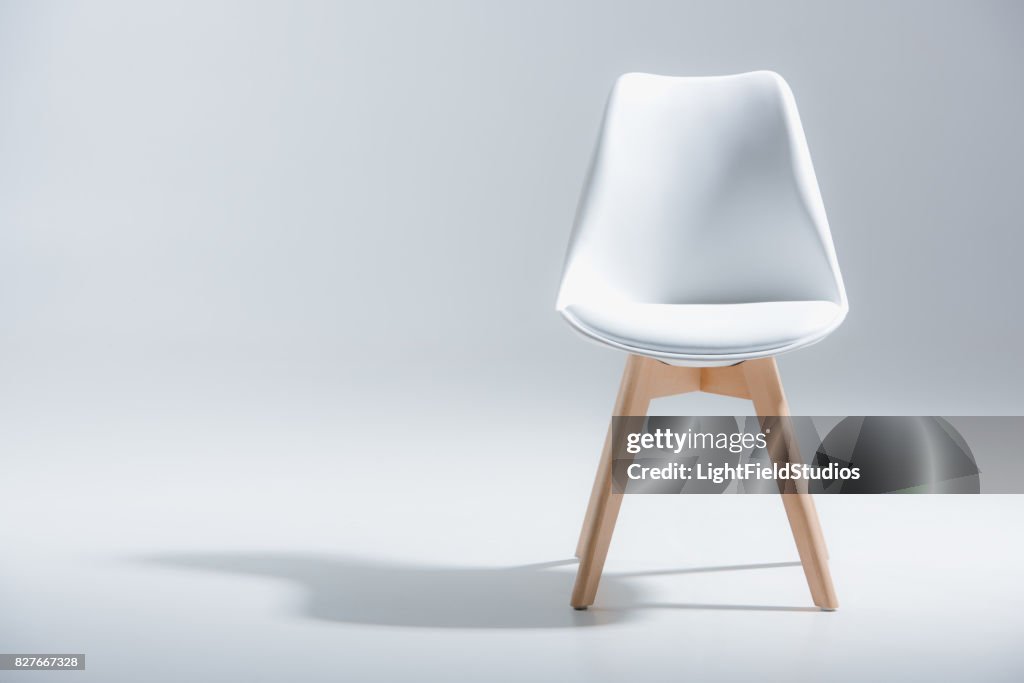 Stylish chair with white top and light wooden legs standing on white