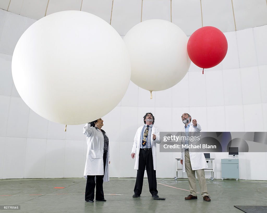 Scientist look upwards at balloons