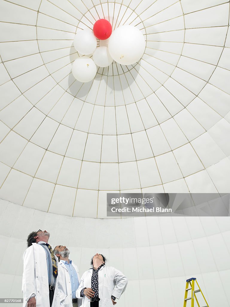 Scientist looking upwards at balloons