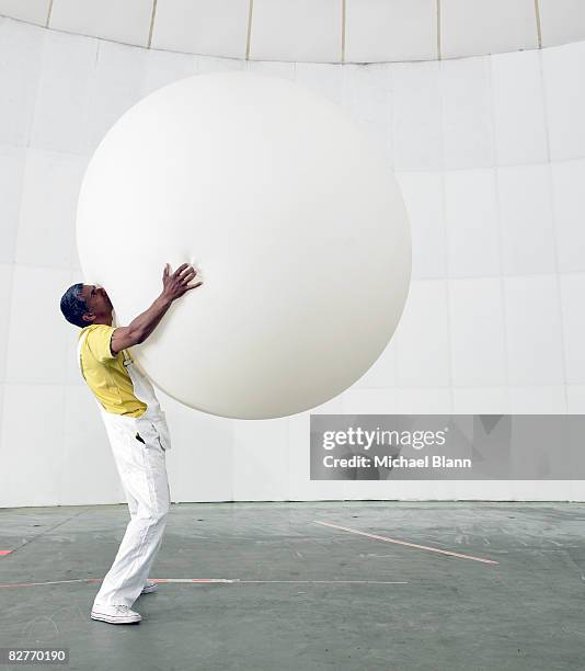 man holding up huge balloon - inflate stockfoto's en -beelden