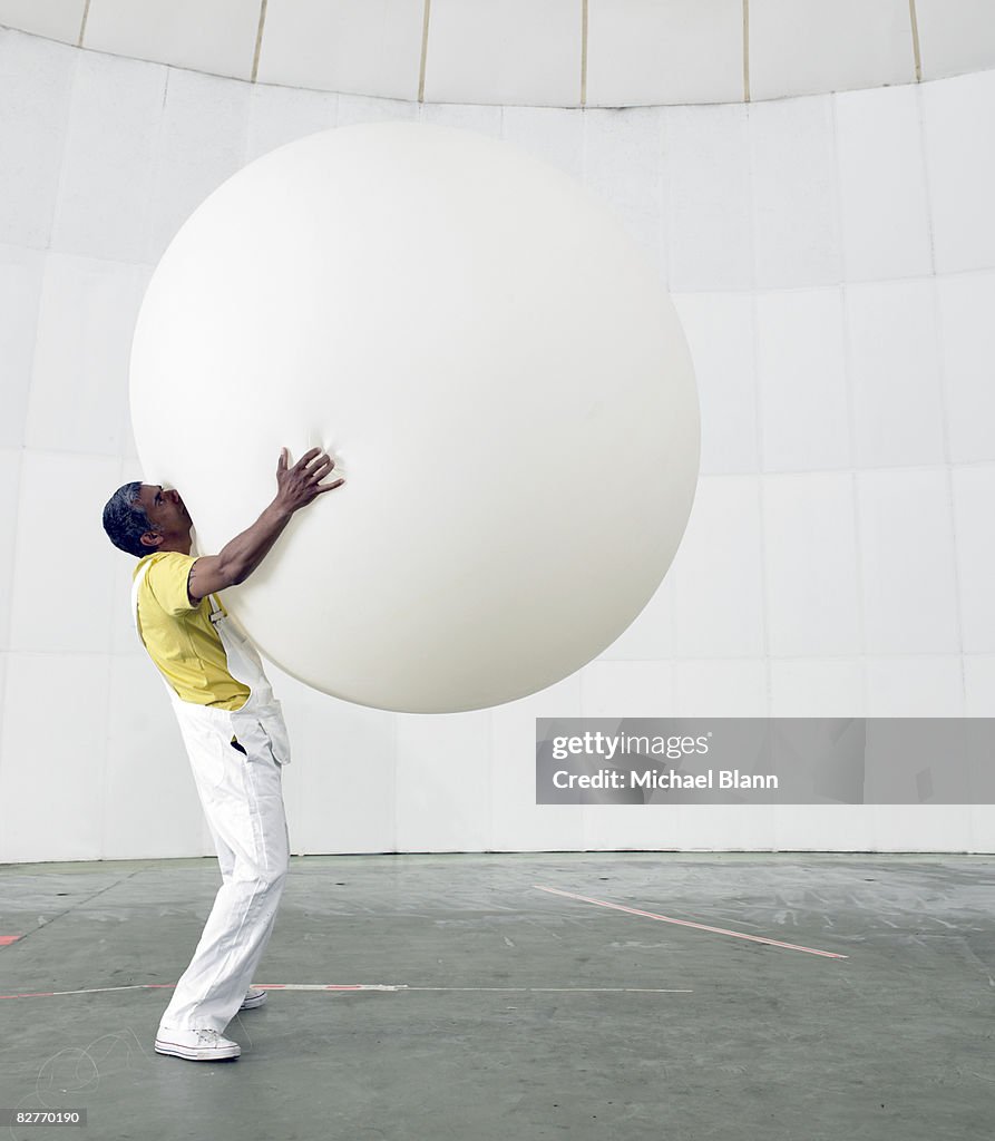 Man holding up huge balloon