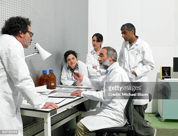 scientists discussing around table in lab - scientist standing next to table stock pictures, royalty-free photos & images