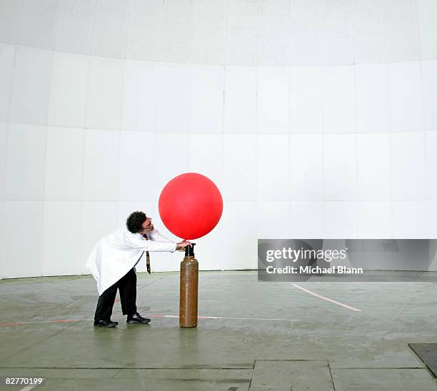 scientist blowing up weather balloon with air - inflate stockfoto's en -beelden