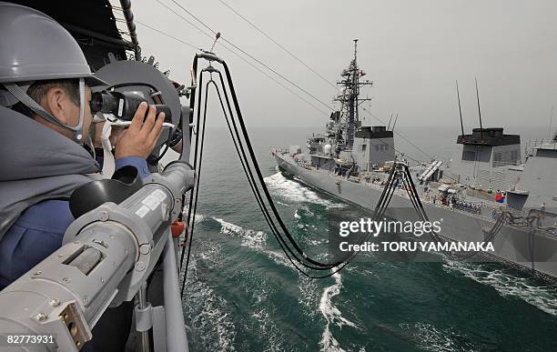 Crew member of the replenishment ship Tokiwa from Japan's Maritime Self-Defense Force looks at supply activities of fuel and water to MSDF's...