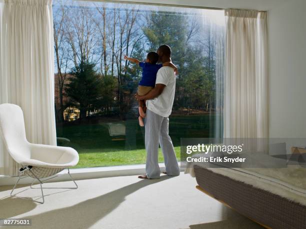 father holding son by window - westchester stock pictures, royalty-free photos & images