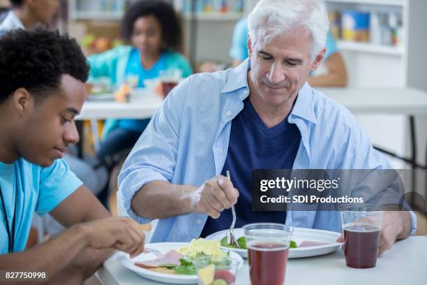 gaarkeuken vrijwilliger deelt een maaltijd met dakloze man - no kid hungry benefit dinner stockfoto's en -beelden