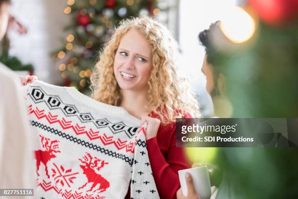 woman receives ugly christmas sweater at party - feio imagens e fotografias de stock