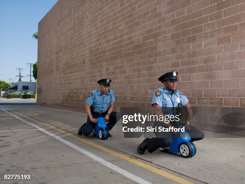 Men in police uniforms riding toy motorcycles Men in police uniforms riding toy motorcycles