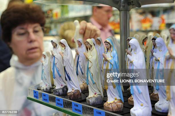 Woman looks at statues of the Virgin Mary displayed in a store in Lourdes on September 11, 2008 ahead of the visit of Pope Benedict XVI who will...