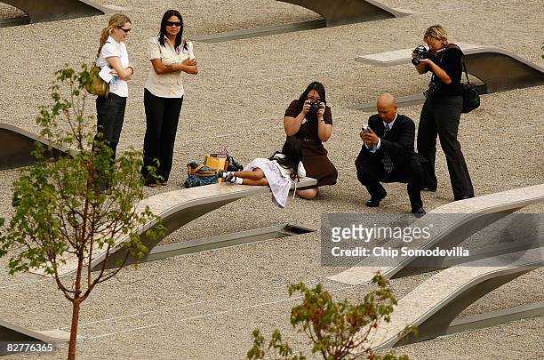 Family members pose for photographs on the "memorial units" at the Pentagon Memorial after the dedication ceremony September 11, 2008 in Arlington,...