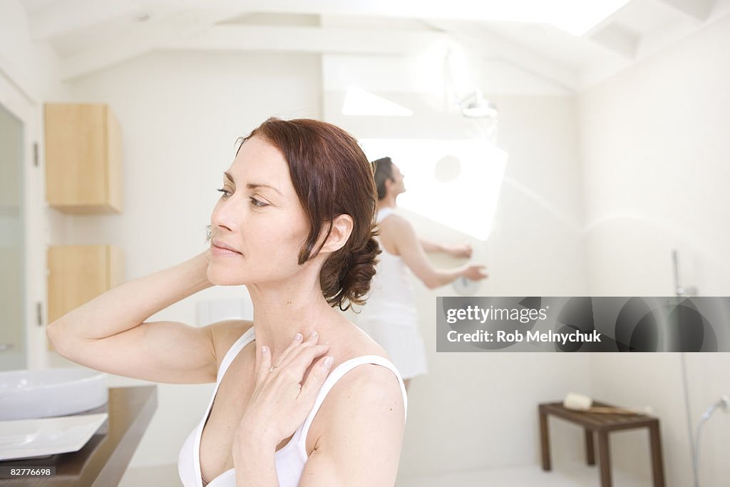 Woman looking at herself in bathroom mirror.