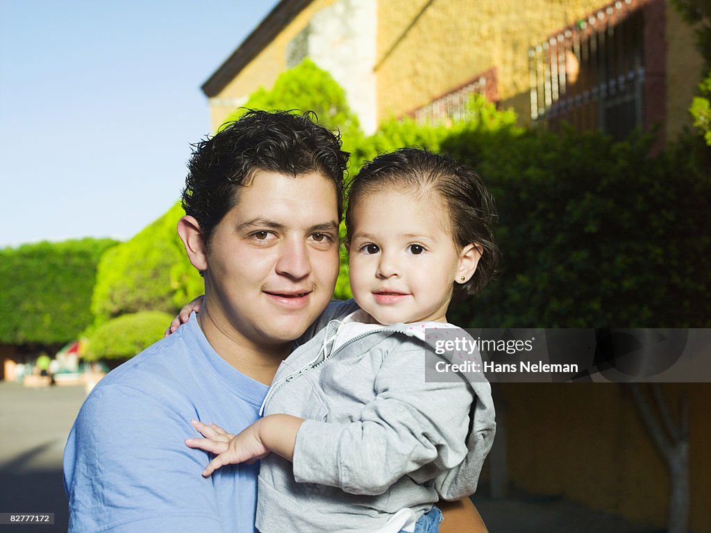A young hispanic father holding his daughter