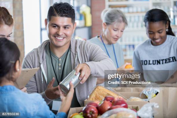 mid volwassen hispanic man vrijwilligers tijdens voedsel rijden - male volunteer stockfoto's en -beelden