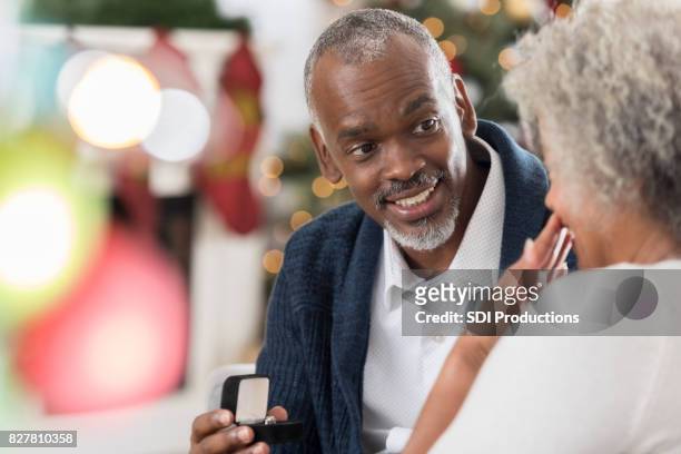 senior man geeft zijn vrouw sieraden op kerst - old man woman christmas stockfoto's en -beelden