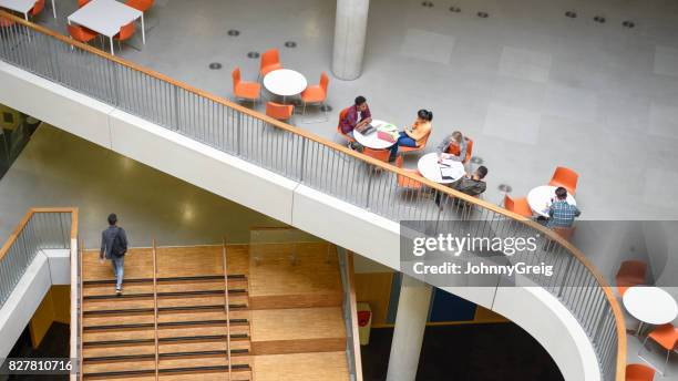 groep studenten studeren op open plan mezzanine met jonge man op de trap - mezzanine stockfoto's en -beelden