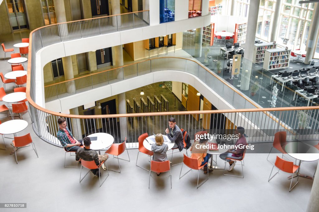 High angle view of modern college interior, students sitting around tables