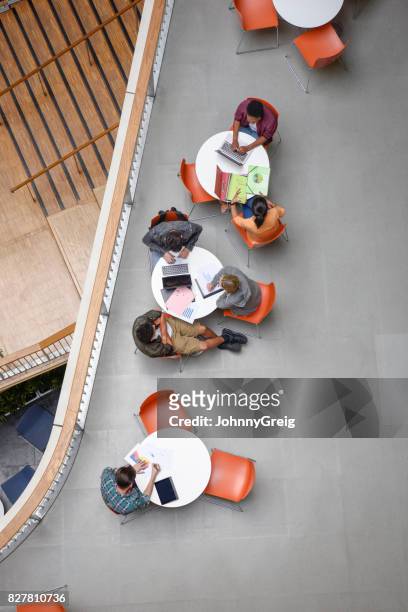 studenten aan het moderne college zitten aan ronde tafels met behulp van laptops en werken - ronde tafel stockfoto's en -beelden