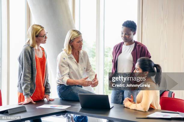 volwassen vrouwelijke leerkracht uit te leggen aan drie vrouwelijke studenten - docent stockfoto's en -beelden