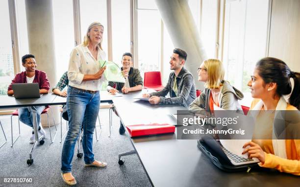 college classroom with mature female teacher and young multi ethnic students - education stock pictures, royalty-free photos & images