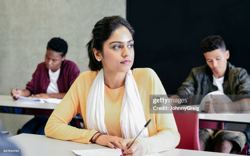 Young woman in yellow sweater doing exam, looking away